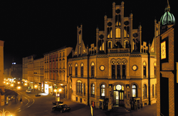 Das Bild zeigt das erleuchtete Postgebäude bei Nacht.