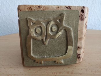 messingfarbene Plakette goldene Eule auf Holzblock