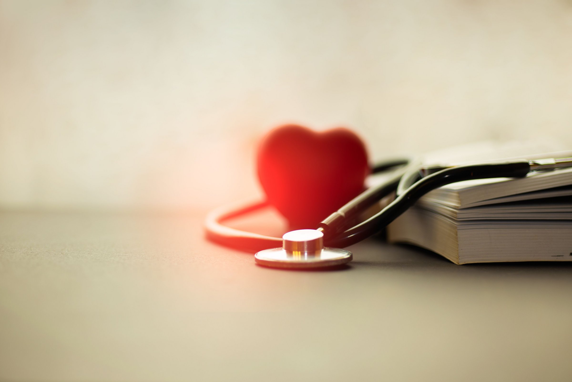 Das Bild zeigt Bücher, ein Stethoskop und ein rotes Herz.
