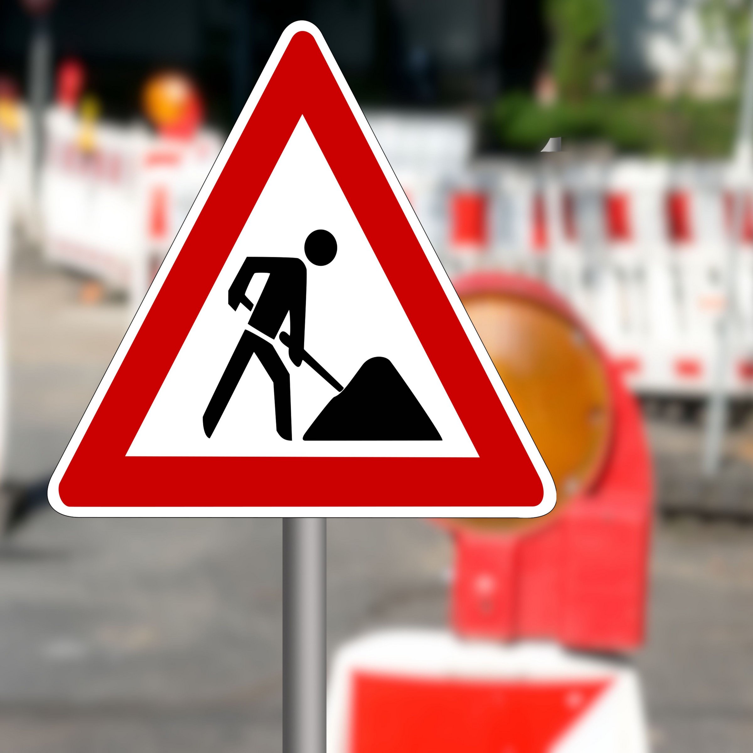 Das Bild zeigt ein Baustellenschild und im Hintergrund eine Baustelle.