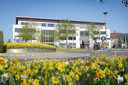Das Bild zeigt die Stadtinformation Iserlohn und den Kreisverkehr mit vielen gelb blühenden Blumen.