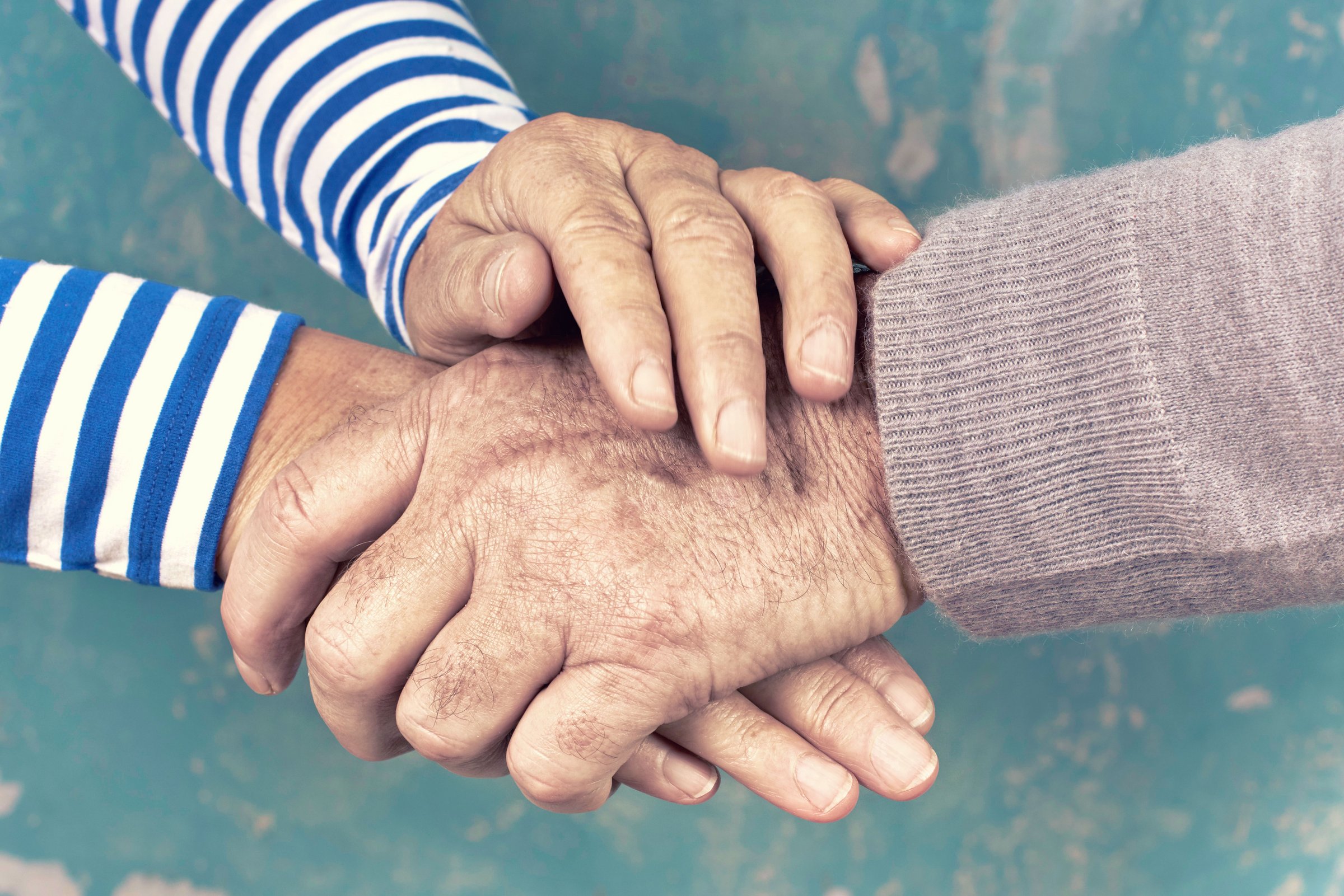 Das Bild zeigt zwei ältere Menschen, die sich die Hände halten