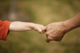 Das Bild zeigt eine Kindehand, die den Finger eines Erwachsenen greift.
