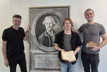 Stadtarchivar Rico Quaschny, Patric Rode und Eric Witt, die Vortrag und Lesung vorbereitet haben, vor einem Porträt von Johann Stephan Pütter.