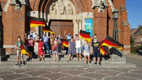 Das Bild zeigt Einwohner*innen der Stadt Laventie, die winkend und mit Deutschlandfahnen die Freundinnen und Freunde in Sümmern grüßen. 
