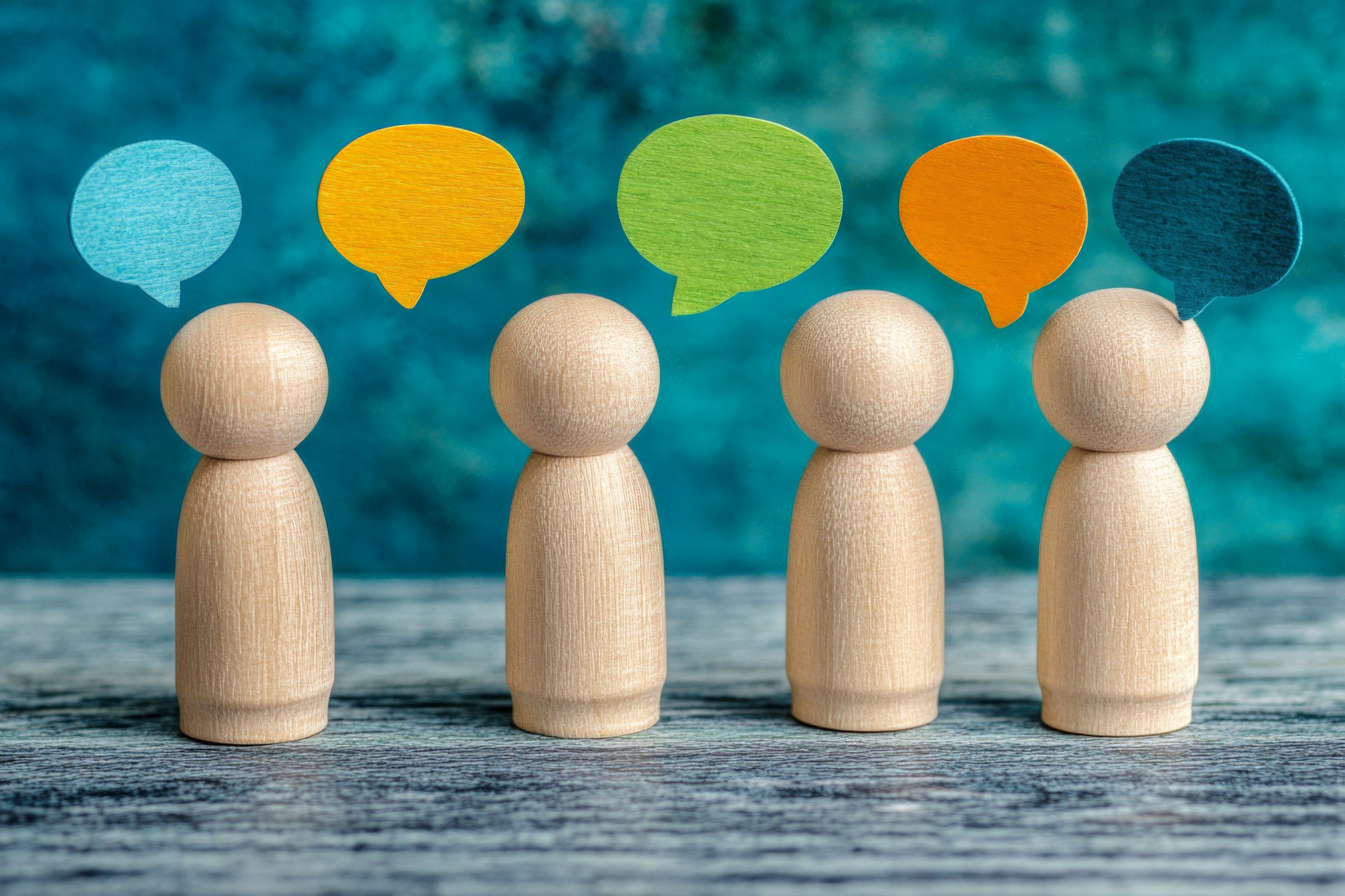 Das Bild zeigt Holzfiguren und Sprechblasen
