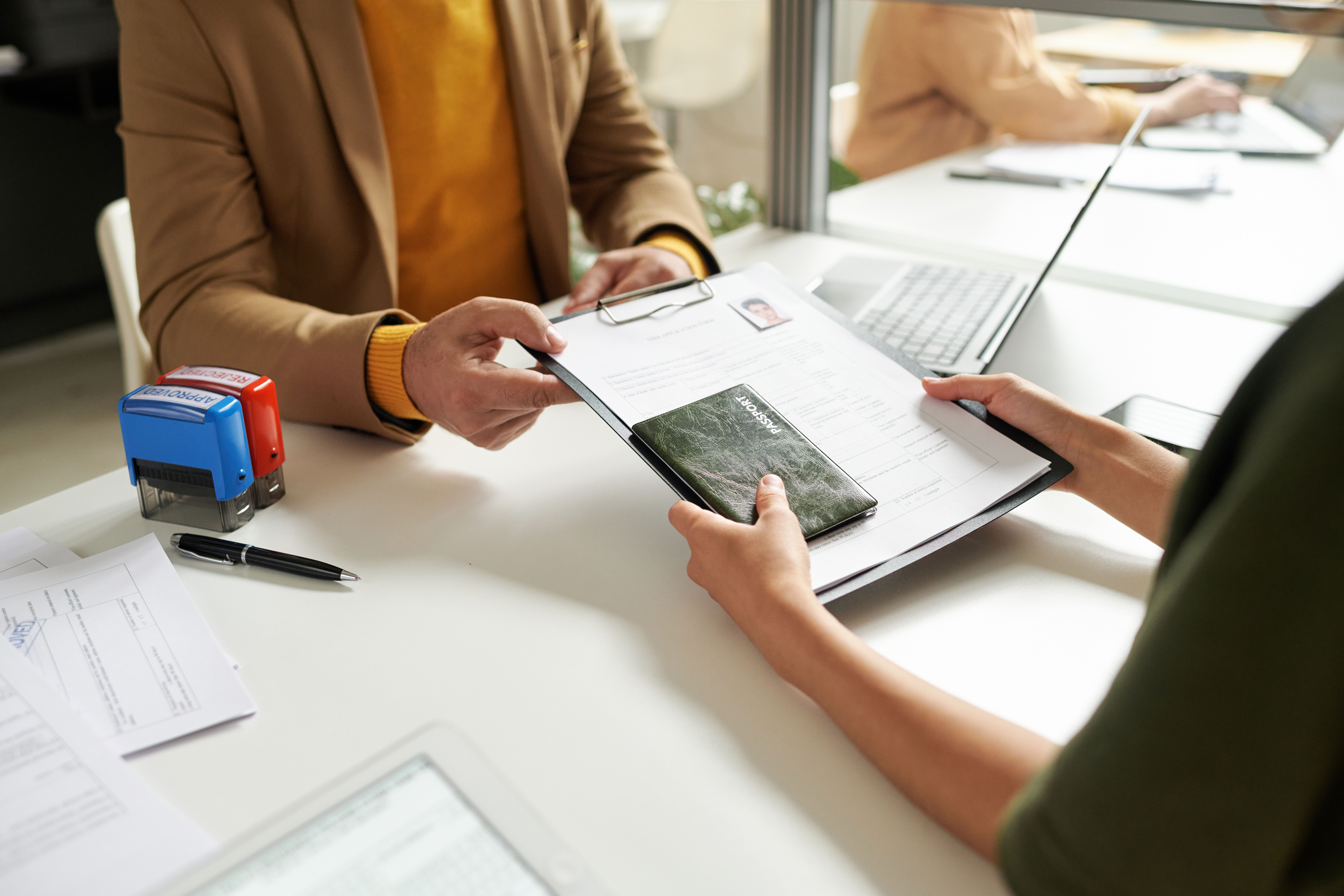 Das Bild zeigt zwei Menschen an einem Schreibtisch, die sich Dokumente übergeben.