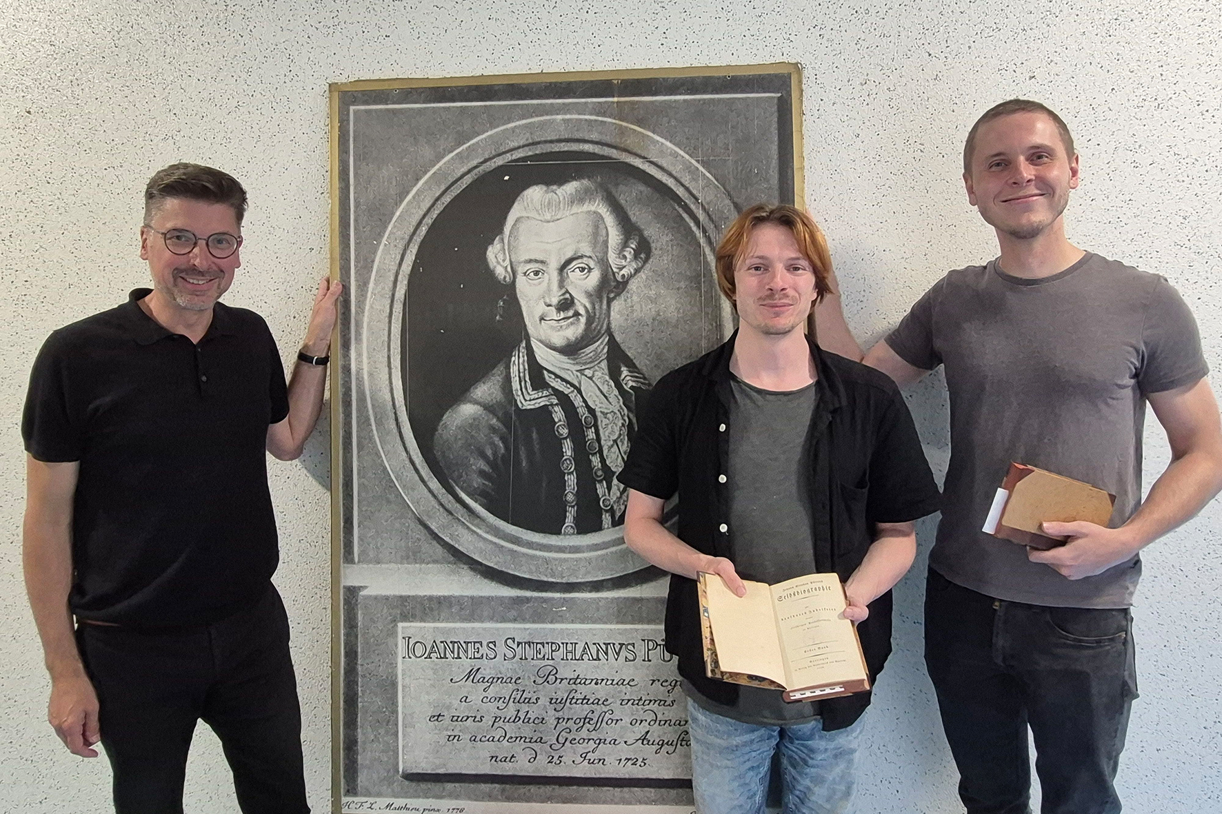 Stadtarchivar Rico Quaschny, Patric Rode und Eric Witt, die Vortrag und Lesung vorbereitet haben, vor einem Porträt von Johann Stephan Pütter.