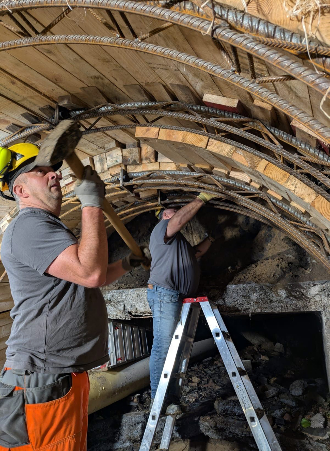 Die Stollensicherung besteht aus einem System aus Schwellen, statisch bemessenen Stahlbögen sowie Holzverzug und wird in präziser Handarbeit eingebracht. 